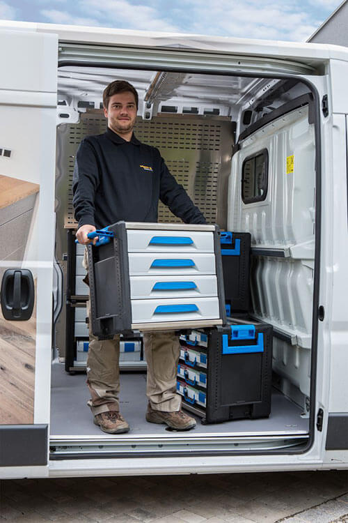 Eine Person lädt einen WorkMo-Baustein aus einem Transporter aus